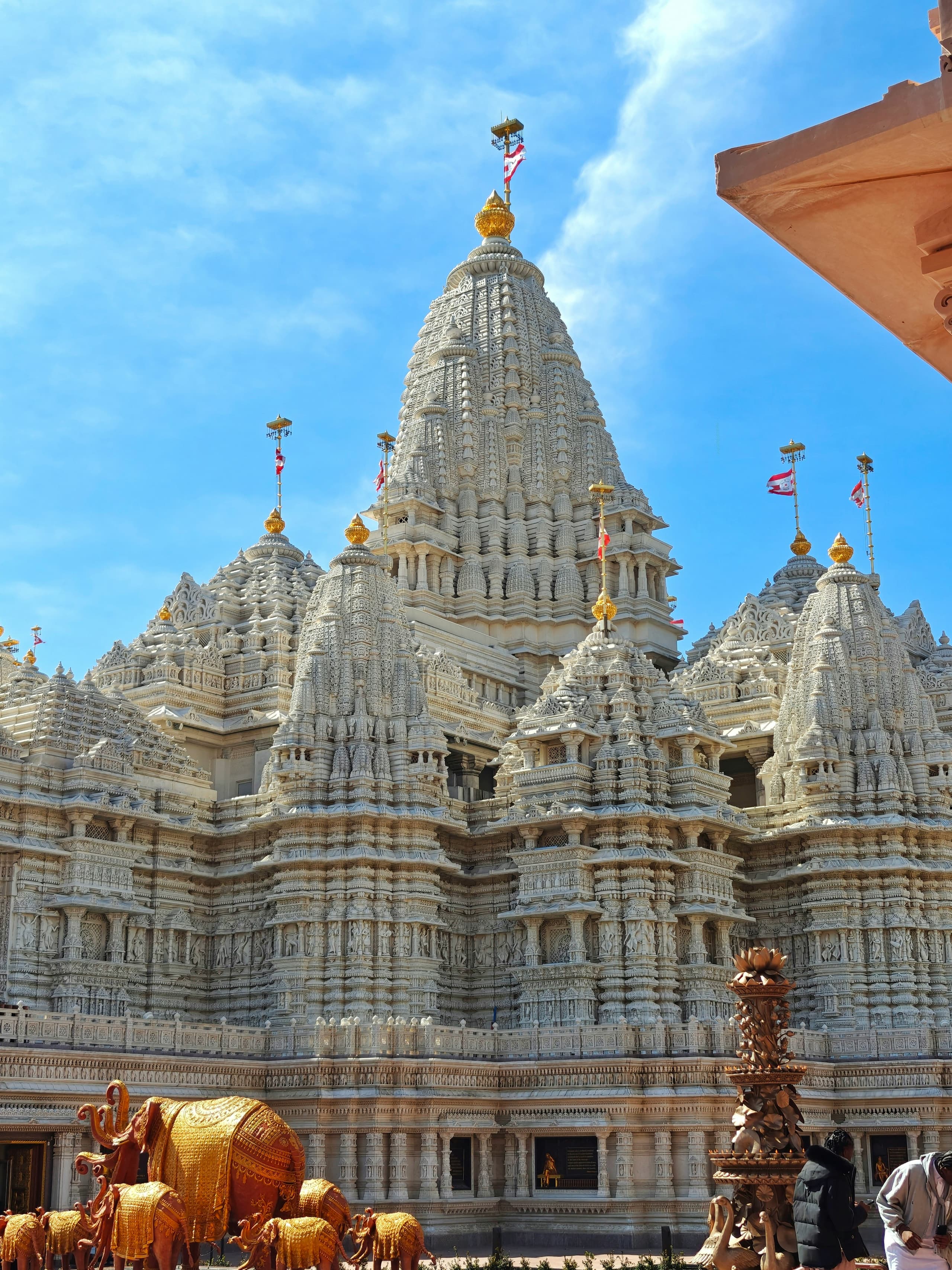 An intricately carved white marble mandir with golden elephant sculptures in the foreground